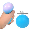 A hand is holding a light blue, translucent stress relief ball next to a measuring scale showing its 6cm diameter.