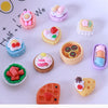 A collection of miniature dollhouse snack foods including cakes, candies, and pastries arranged on a white surface.
