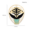 A gold-toned enamel pin featuring a dinosaur battle suit design with black and teal accents.
