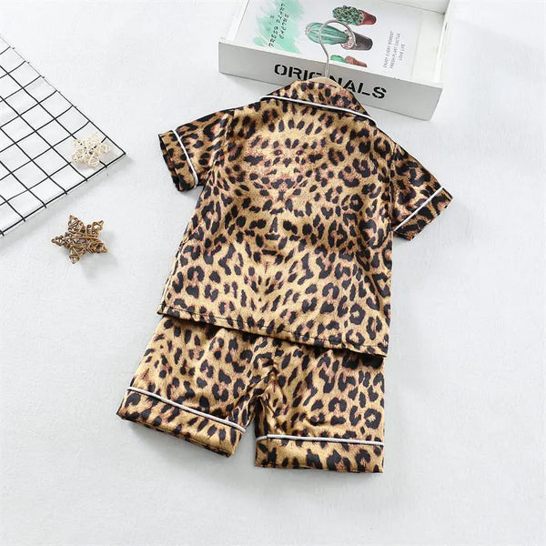 Ensemble de pyjama pour enfant à imprimé léopard, avec des taches marron et noires et une bordure blanche.