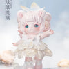 A pink collectible figurine of a girl with light blue eyes and fluffy hair, wearing a white dress, standing on a clear surfac