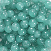 A close-up view of small, round, translucent teal glass beads for DIY jewelry making.