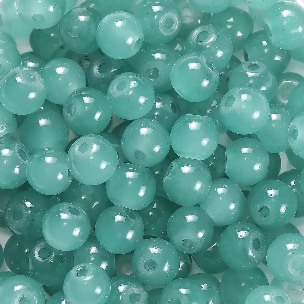 A close-up view of small, round, translucent teal glass beads for DIY jewelry making.