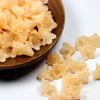 A pile of light orange frosted acrylic flower beads in a wooden bowl.