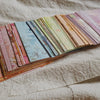 A collection of rainbow textured paper sheets in various shades and patterns laid out on a light fabric.