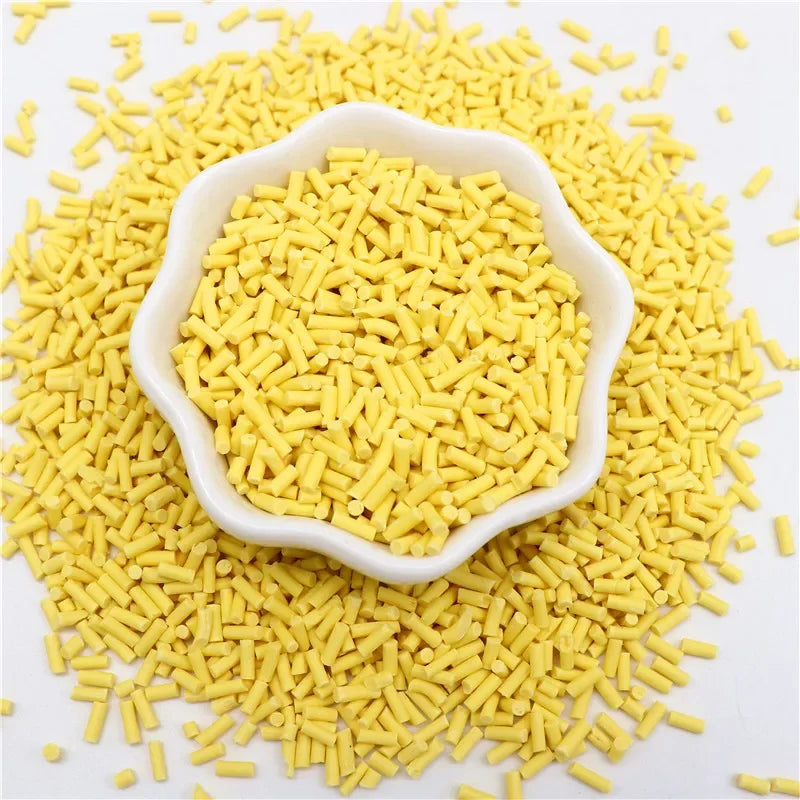 Yellow polymer clay slice sprinkles scattered on a white surface.
