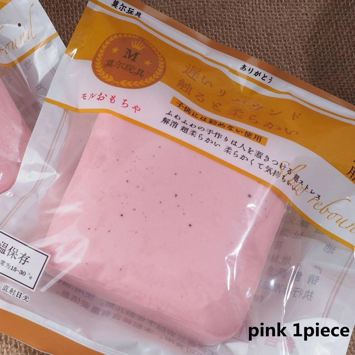 A pink squishy stress relief toy is packaged in a clear plastic bag with Japanese text.