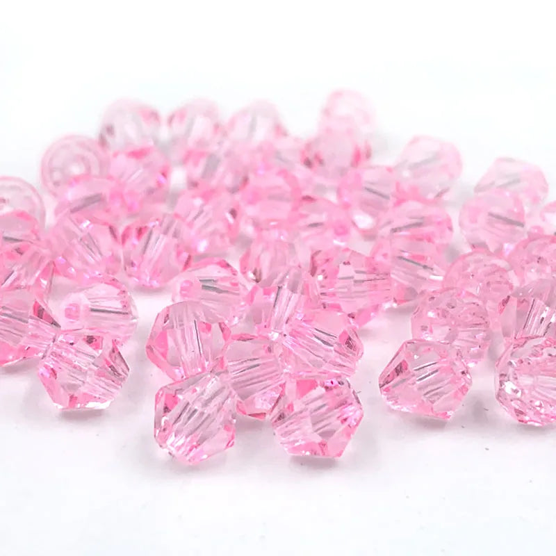 A pile of faceted pink bicone crystal glass beads for jewelry making.