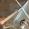 A hand holds a luminous anime katana prop with an LED blade and a textured grip against a marbled background.