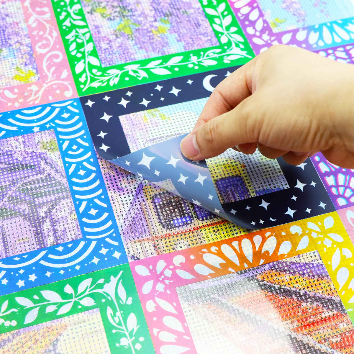 A hand is peeling a sheet of reusable non-stick release paper for diamond painting from a colorful grid.
