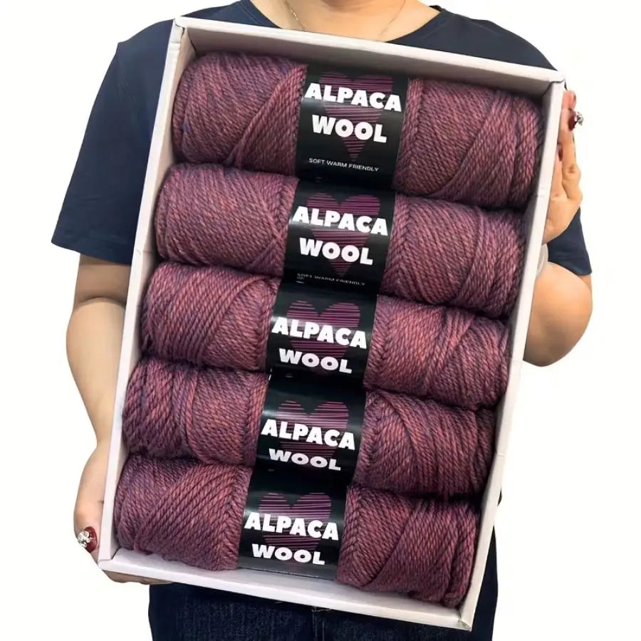A box containing five skeins of purple alpaca wool yarn for knitting and crochet.