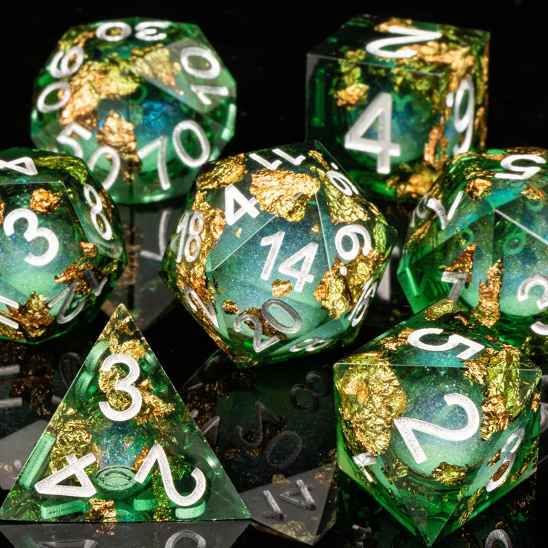 A collection of green polyhedral dice, some covered in gold leaf, are displayed on a dark surface.