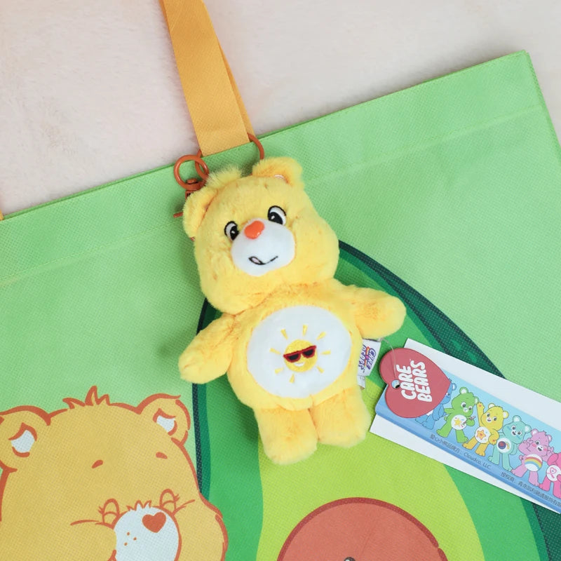 A yellow Care Bears plush toy keychain is attached to a green fabric bag.