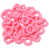 A pile of pink acrylic doughnut spacer beads for jewelry making