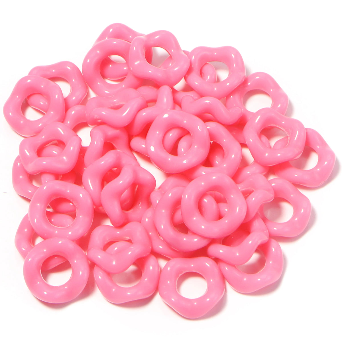A pile of pink acrylic doughnut spacer beads for jewelry making