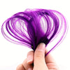 A hand holds a vibrant purple clip-in hair extension set, showing the fine strands and color.