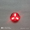 A close-up view of a red magnetic LED diorama light with a remote control, showing the illuminated components.
