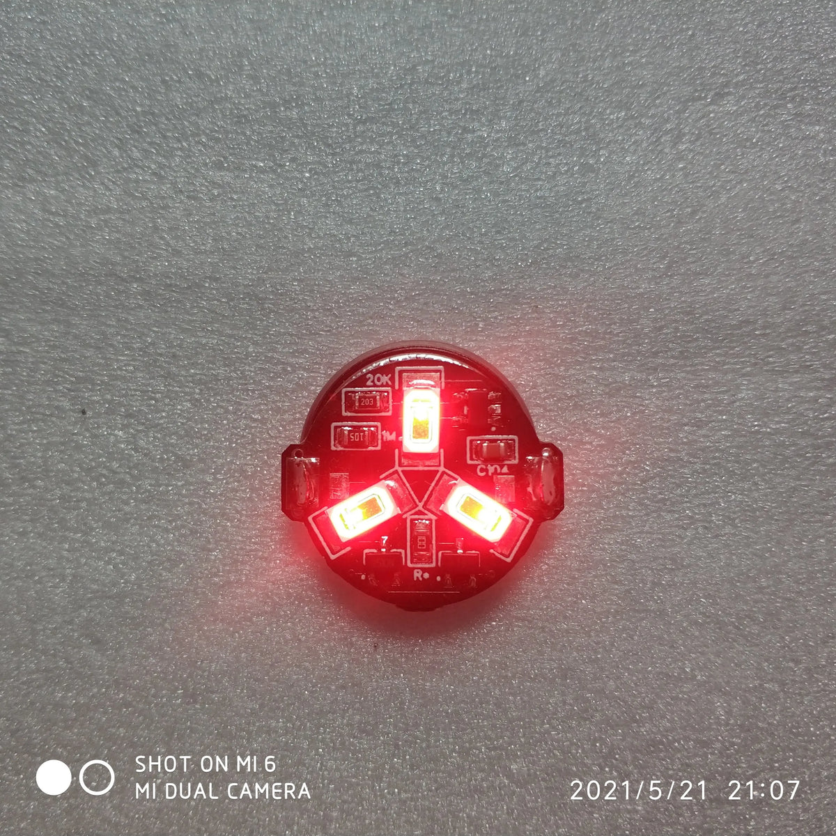 A close-up view of a red magnetic LED diorama light with a remote control, showing the illuminated components.