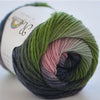 A ball of hand-dyed merino wool yarn in shades of green, pink, and gray, coiled for knitting or crochet.