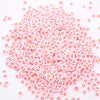 A pile of small pink and white polymer clay flower charms for DIY crafts