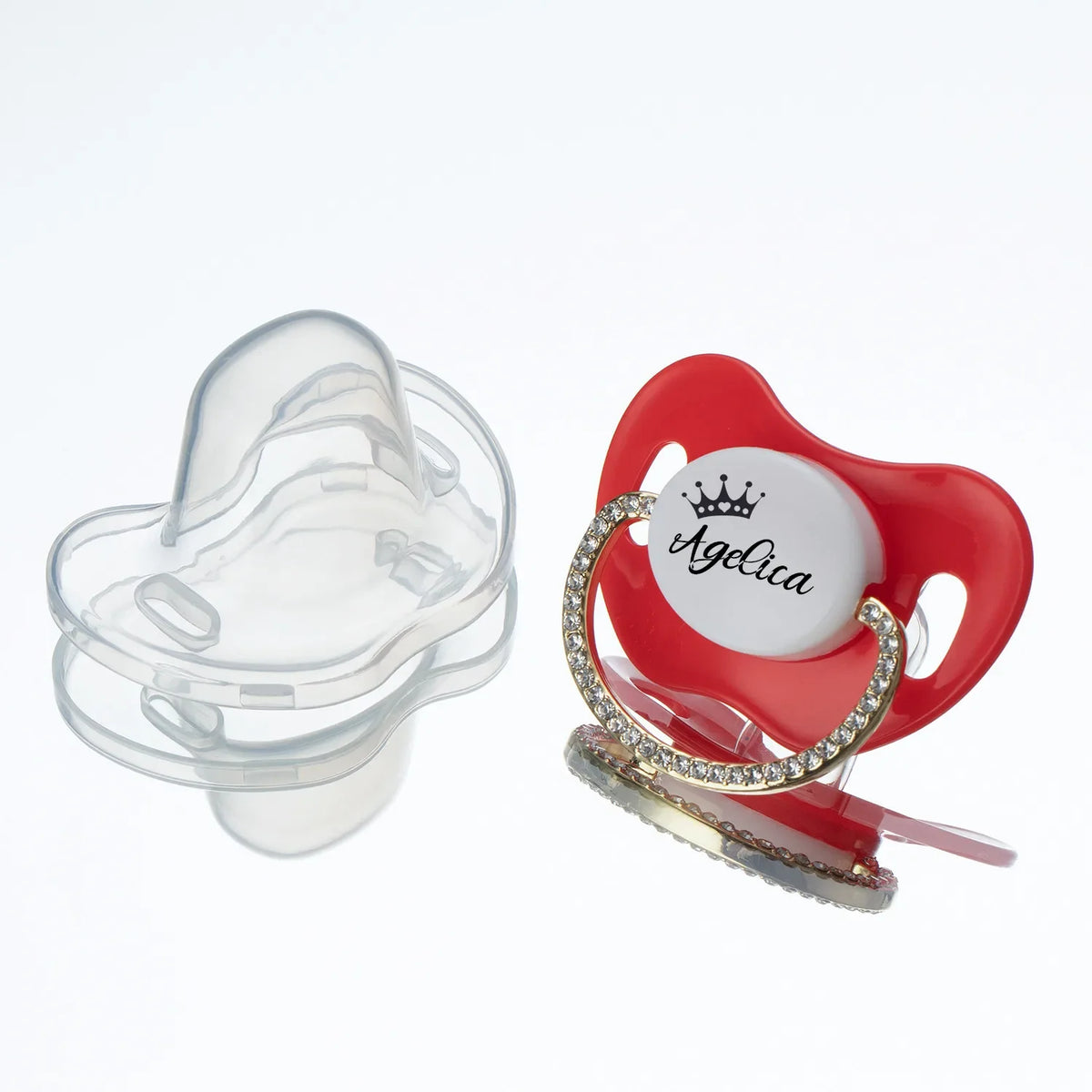 A red baby pacifier with a clear silicone shield and a rhinestone crown design.