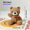 A dark brown Mini Bear plush toy shown against a yellow background with dimension markings.