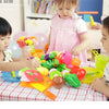A child is playing with a pretend play kitchen set featuring colorful plastic fruits and vegetables.