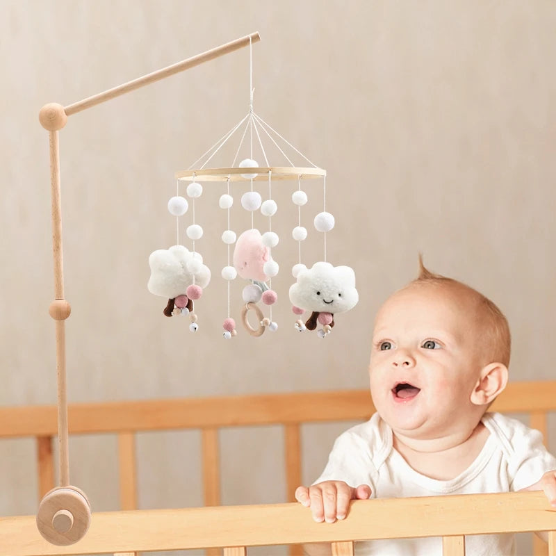 A wooden felt forest animal crib mobile hanging above a baby in a crib.