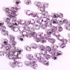 A pile of small, faceted purple crystal bicone glass beads for jewelry making.