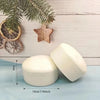 A white yogurt cake squishy stress relief toy is shown next to a green pine branch decoration.