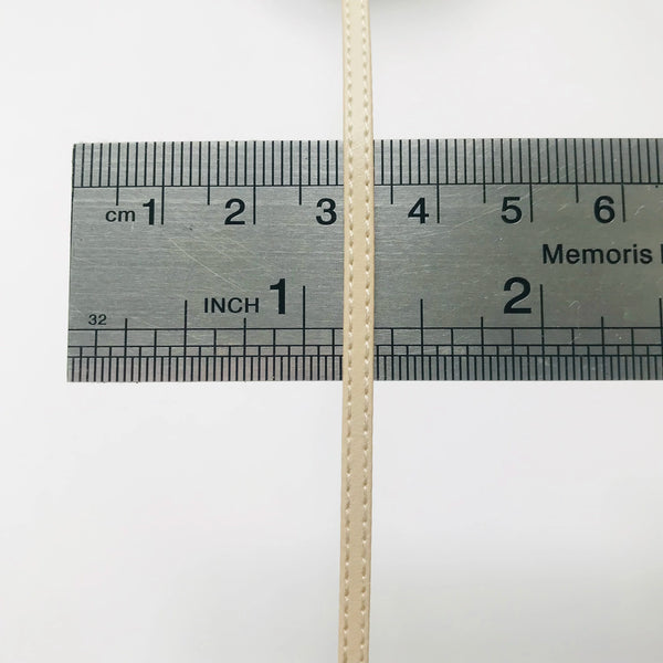 A close-up of a light beige strap measuring tool showing centimeter and inch markings.