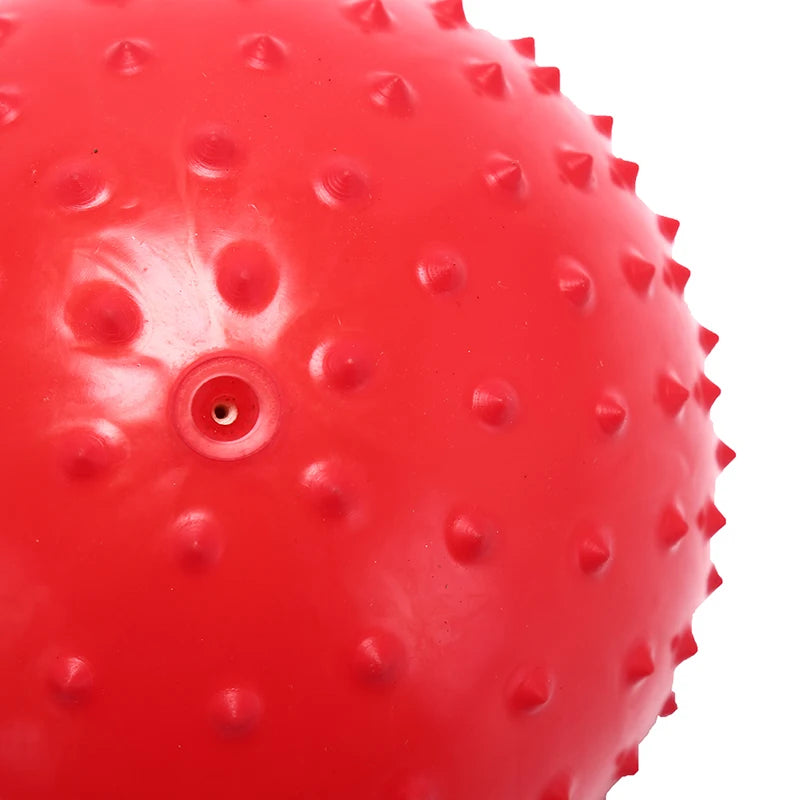 A close-up view of a bright red inflatable sensory ball with textured bumps and a small hole.