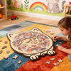 A wooden cat-shaped jigsaw puzzle featuring a collage of cat images on a colorful rug.