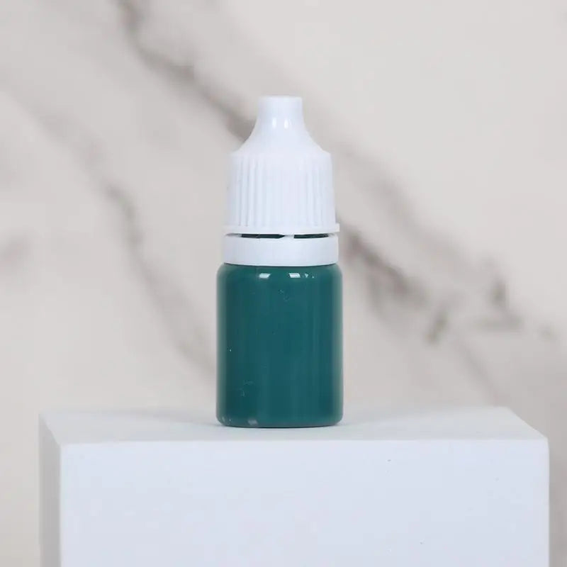 A small glass bottle of teal water marbling paint for kids with a white cap sitting on a white surface.