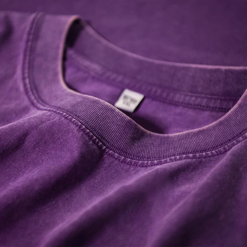 A close-up of a purple men's retro washed heavyweight cotton t-shirt showing the neckline and tag.