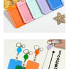 A collection of colorful retractable ID badge holders with keychain clips arranged in a wooden tray and displayed on a white 