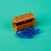 A wooden treasure chest built from building blocks is shown next to blue gemstone-like pieces on a teal background.
