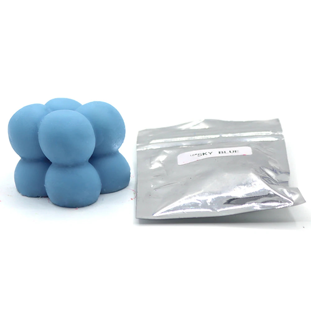 A pile of light blue candle dye chips next to a sealed plastic bag labeled SKY BLUE.