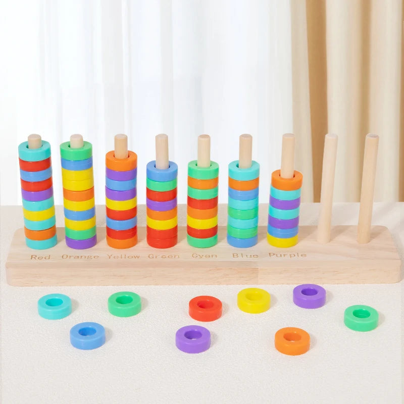 Wooden ring toss game with colored wooden rings and pegs arranged in a row for sorting or stacking.