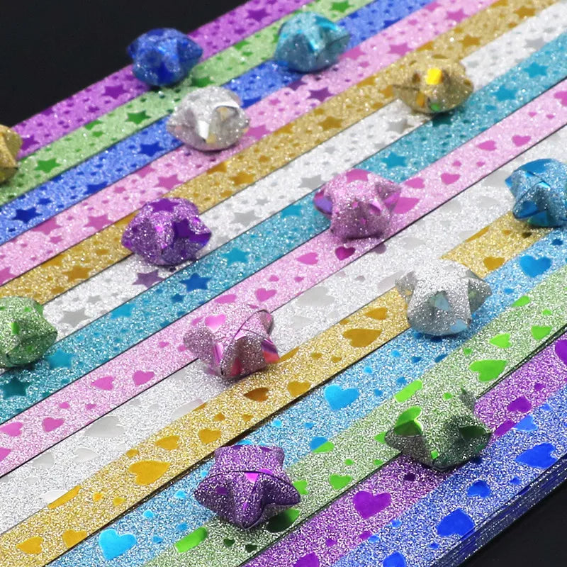 Colorful glitter origami star paper strips arranged in horizontal stripes for crafting and decorating