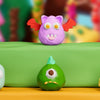 A collection of colorful polymer clay sculptures, including a pink, purple, green, and yellow face, displayed on a green surf