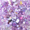 A close-up of small, colorful acrylic bow beads in various shades of purple and pink.