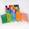 A clear plastic box filled with various colored fuse beads for crafting, including green, yellow, orange, pink, and blue.