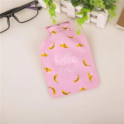 A pink portable hot water bottle with a cozy cover featuring illustrations of fruit.
