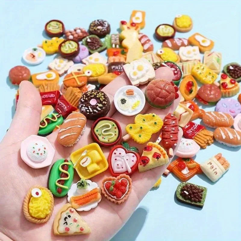 A hand holds a large assortment of miniature dollhouse food items including cakes, snacks, and candies on a light blue backgr