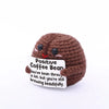 A brown crochet animal plush with black eyes and a red heart stitched on its cheek, featuring text about coffee beans.