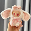A soft pink fluffy rabbit costume for a doll with large ears and expressive eyes is held in a hand.