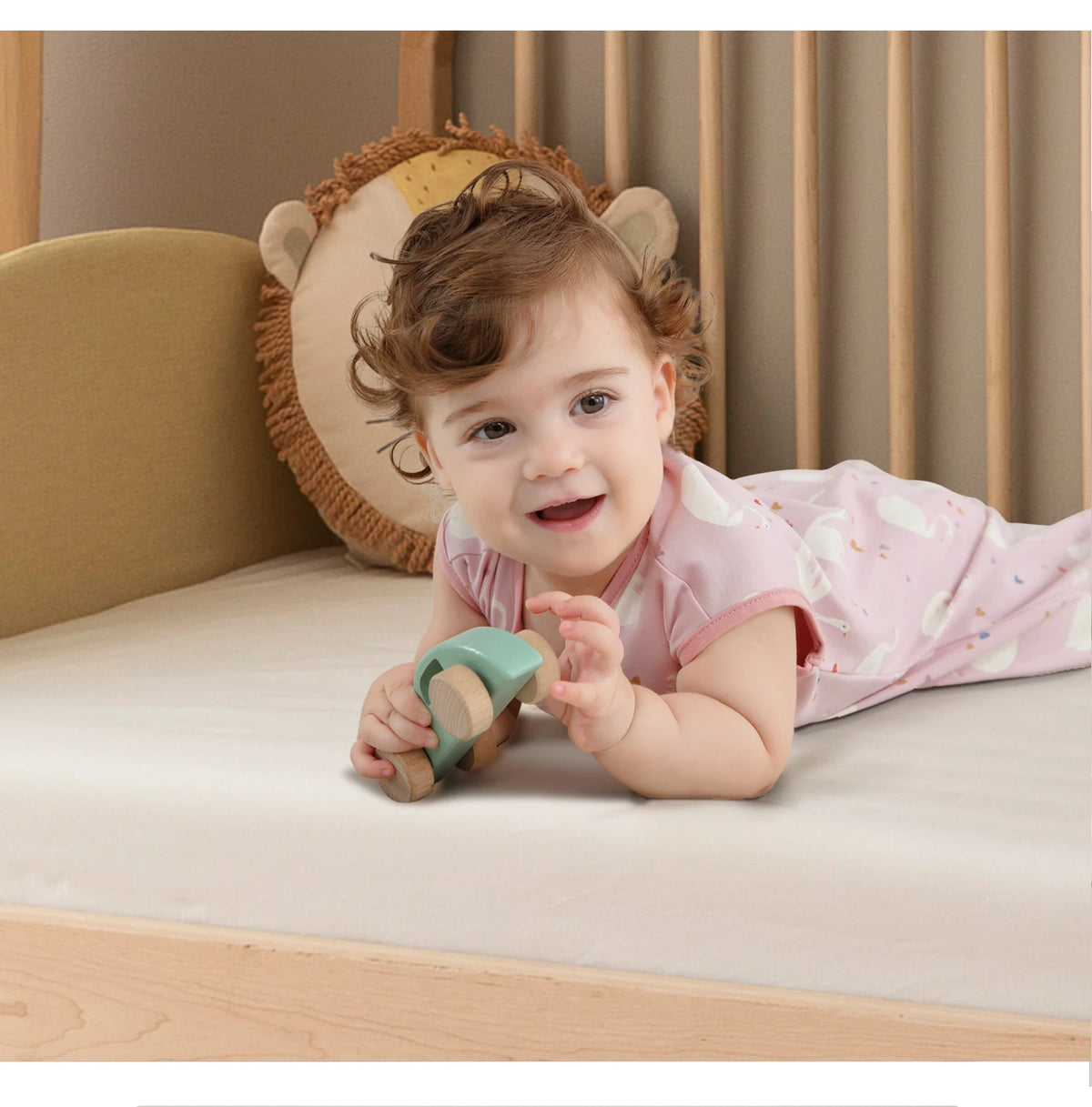 A baby is playing with a wooden toy on a light-colored surface in a nursery setting.