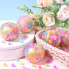 A collection of colorful squeeze stress relief balls with mesh netting arranged on a pink surface.