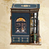 A miniature DIY bookstore book nook kit featuring a dark teal facade and an arched window with internal lighting.